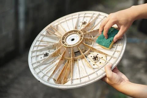 Close up hand hold sponge to scrub dirty strain on part of washing machine. Conc Foto stock
