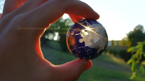 Close-Up of Hand Holding 3D Globe Puzzle with Sun Rays Stock Footage 295115897