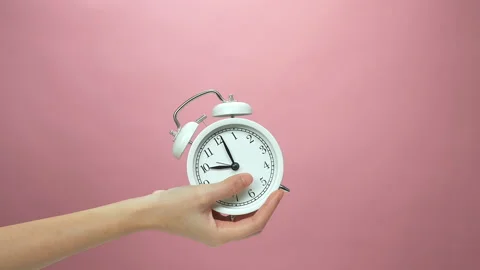 Close Up of hand holding alarm clock on pink background. 스톡 동영상 153960256