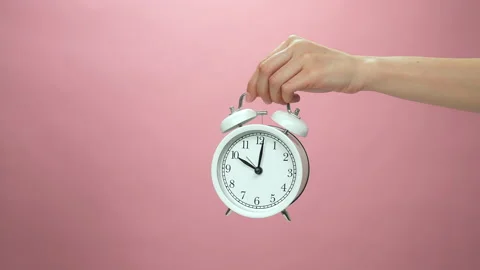 Close Up of hand holding alarm clock on pink background. 스톡 동영상 153963661