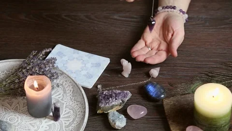 Close up of hand holding and using amethyst crystal pendulum on silver chain. 스톡 동영상 147385551