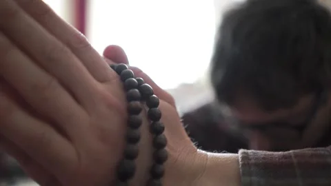 Close up of hand holding and using prayer beads for worship and quiet meditation Stock Footage 318920076