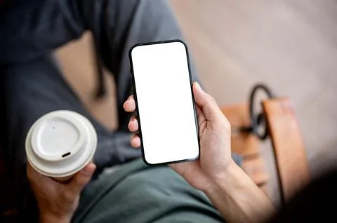 Close up of a hand holding blank screen smartphone reading news with a coff.. Stock Photos
