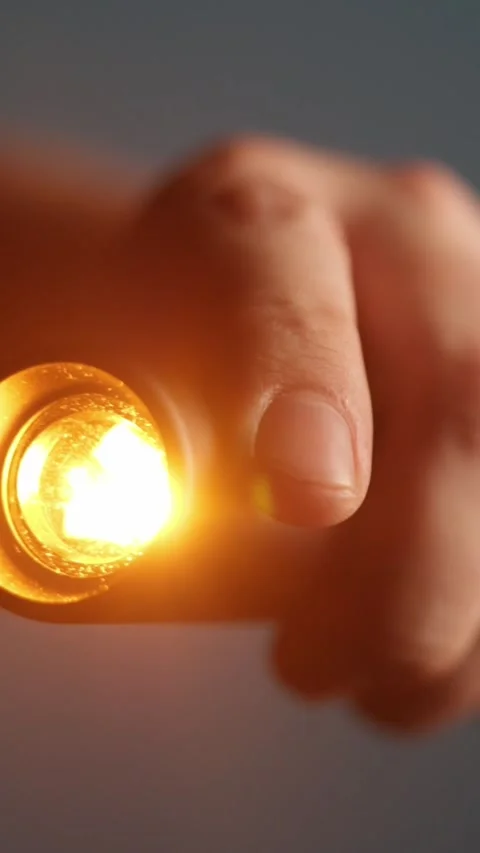 Close-up of a hand holding a bright orange flashlight beam in the dark Stockbeeldmateriaal 343838199