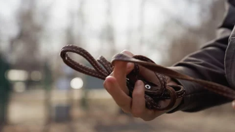 Close up of hand holding coiled brown leather strap with visible texture and Stock Footage 345845678