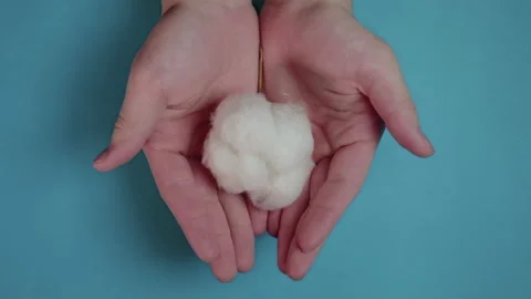 Close-up of hand holding cotton ball on blue background Stock Footage 149785629