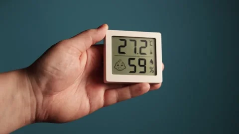 Close-up of hand holding digital thermometer and hygrometer displaying Stock Footage 340267065