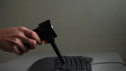 Close-up of hand holding electric air duster blowing dust from black computer Vídeo Stock 342756502