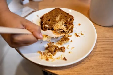 Close-up of a hand holding a fork and eating a slice of cake. Stock Photos