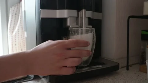 Close-up of a hand holding a glass as a automatic coffee machine dispenses Stock Footage 328287554