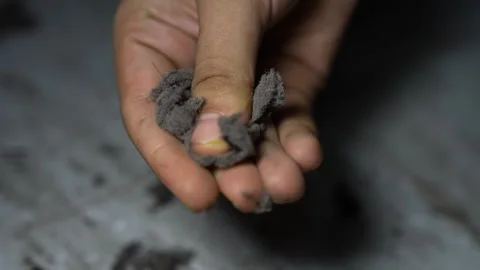 Close-up of a hand holding gray crumbly ash or clay, showing texture and to.. Stock-Footage 338319409
