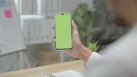 Close up hand holding green screen on mobile phone in office Stock Footage 146888239