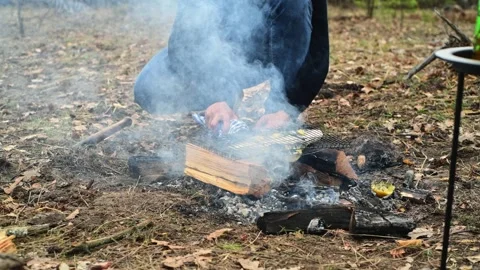 Close up of a hand holding a grill grate with fish over hot campfire coals. Stockbeeldmateriaal 334681121