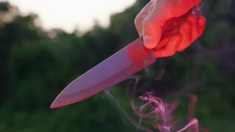 Close Up of a Hand Holding a Kitchen Knife With Rising Smoke Outdoors at Dusk. D Stock Footage 337495071