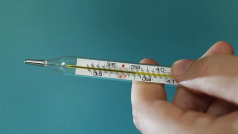 Close-up of hand holding a mercury thermometer showing elevated temperature Stock Footage 340264264