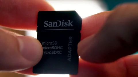 Close-up of a hand holding a microSD card adapter, highlighting its role in Stock Footage 297732722