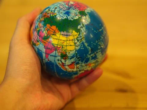 Close Up Hand holding a Mini Globe with Wooden Table Background. Foto stock