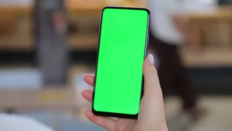 Close-up of hand holding mobile phone with solid green screen Stock Footage 345864507