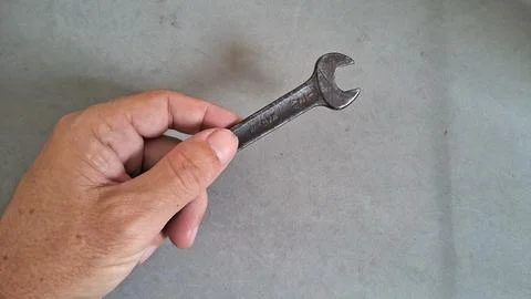 Close up hand holding an old rusty metal open wrench Stock Photos