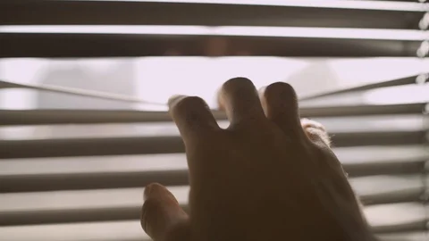 Close up on a hand holding open a window blind to look outside Stock Footage 109164062