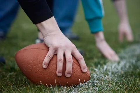 Close up of a hand holding an oval football on the line, during a game of Stock Photos