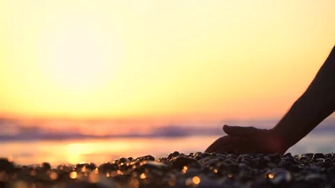 Close-up of hand holding pebbles and dropping them on beach Stock Footage 133374202