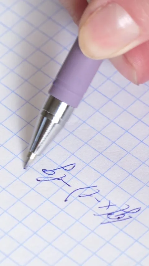 Close-up of hand holding pen while writing numbers and formulas on grid paper Stock Footage 341867297