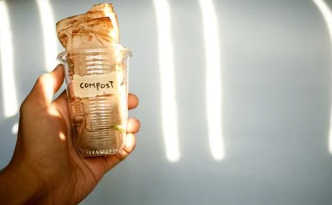 Close up of hand holding plastic drinking glass full of used teabag with text Foto stock