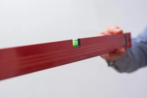 Close-up of a hand holding a red construction level. Tool for DIY, repair, .. Stock Photos
