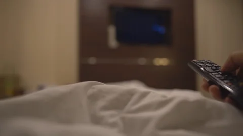 Close up hand holding remote and select chanel for looking television on bed Stock Footage 122886357