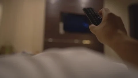 Close up hand holding remote and select chanel for looking television on bed 库存影片 122887027
