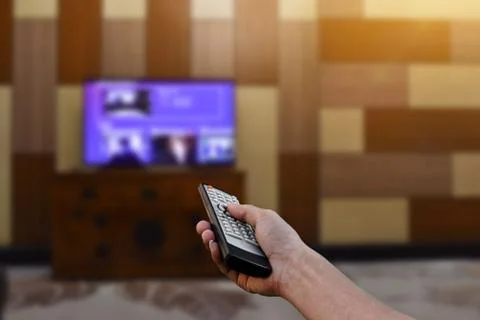 Close up hand holding remote control a television. Selective focus Stock Photos