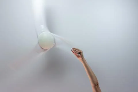 Close-up of hand holding remote control of white ceiling fan. Hand turning on Stock Photos