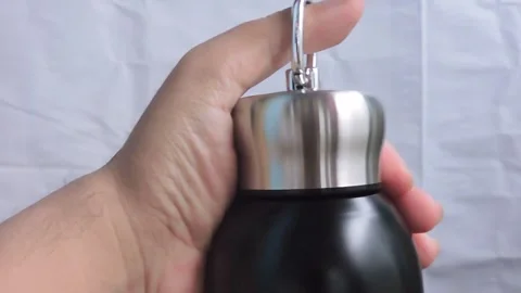 Close-up of a hand holding a sleek stainless steel and black thermos Stock Footage 298888770