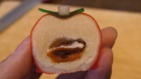 Close-Up of Hand Holding a Slice of Realistic Persimmon-Shaped Mousse Pastry 스톡 동영상 345292244