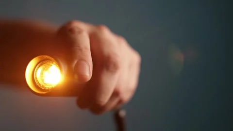 Close-up of a hand holding a small, bright LED light source with warm glow Stock Footage 340265852