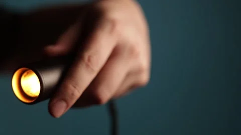 Close-up of a hand holding a small, bright, glowing orange light source Stock Footage 340268416