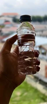 Close‑up of a hand holding a small clear plastic water bottle Фото