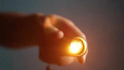 Close-up of a hand holding a small flashlight with a bright orange glow Stock Footage 340265976