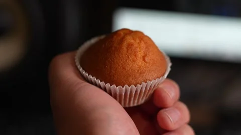Close-up of hand holding small orange muffin in white liner Stock Footage 331530022