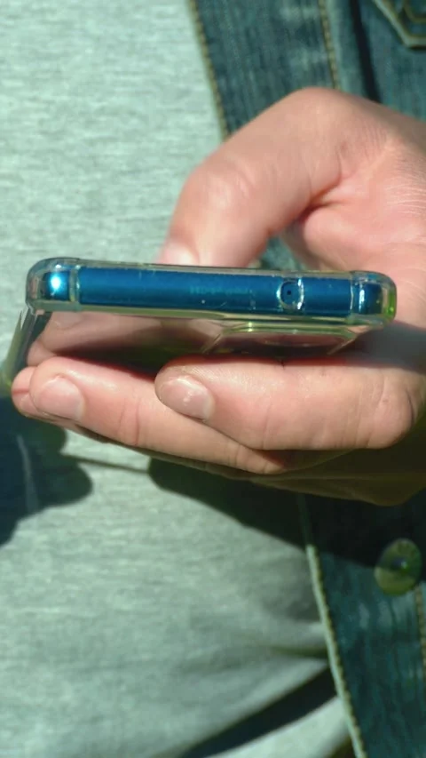 Close-up of hand holding smartphone with blue case, showing fingers interacting 스톡 동영상 339104353