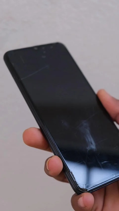 Close up of a hand holding a smartphone with a cracked screen Stockbeeldmateriaal 331004355