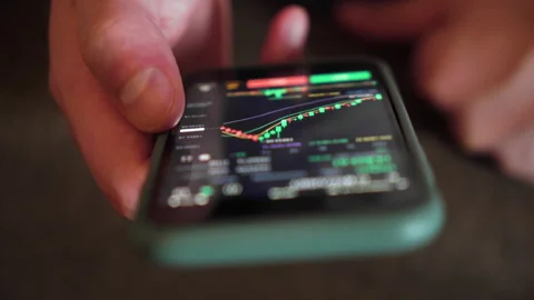 Close-up of hand holding smartphone displaying cryptocurrency chart Vidéo 328294264