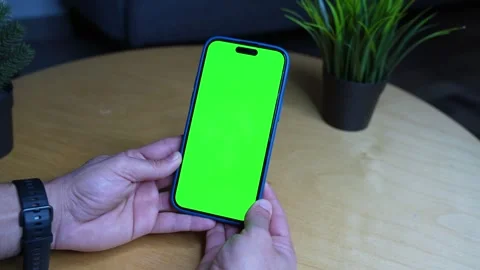 Close-Up of Hand Holding Smartphone with Green Screen – Tabletop Shot for App Stock Footage 309943415