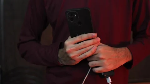 Close Up of Hand Holding Smartphone While Charging with USB Cable Stock Footage 337847364