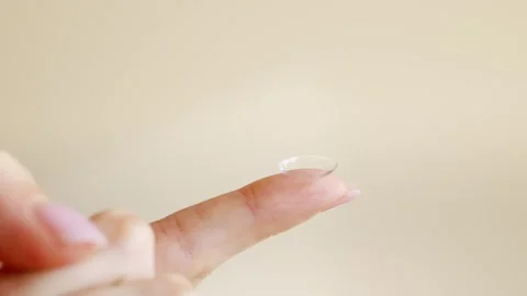 Close-up of a hand holding a soft contact lens on fingertip. Видео 331458759