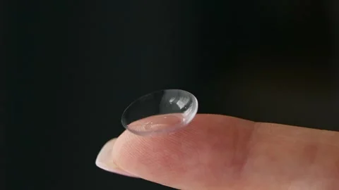 Close-up of a hand holding a soft contact lens on fingertip. Видео 331458795