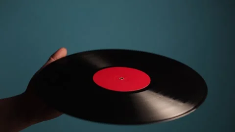 Close up of a hand holding a spinning vinyl record with a red label Stock Footage 340266325