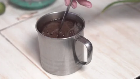 Close-up of a hand holding a spoon stirring coffee in a stainless steel cup Stock Footage 329561349