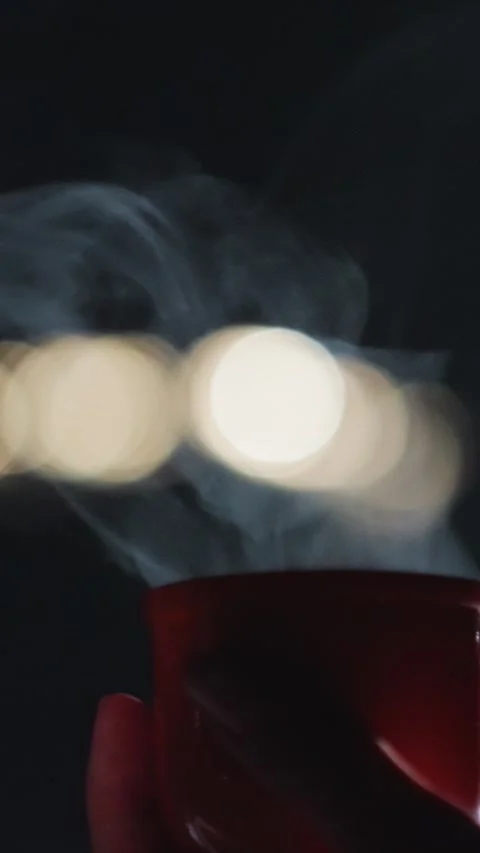 Close up of hand holding steaming hot drinks in red and orange cups with bokeh Stock Footage 345545343